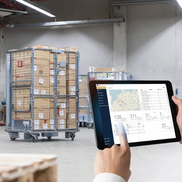 Mitarbeiter im Lager mit Warnweste nutzt Tablet zur Verwaltung von Ladungsträgern